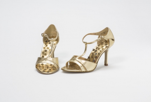 Golden shoes with pins on black velvet